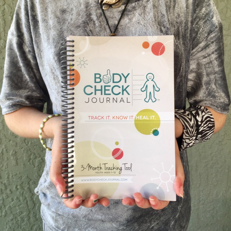 Image of a woman holding a spiral bound journal health tracker, with link to Etsy seller. 