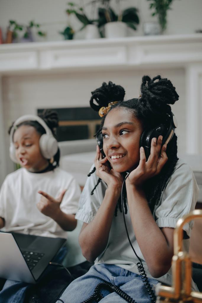 Two African American girls listen together with headphones. 