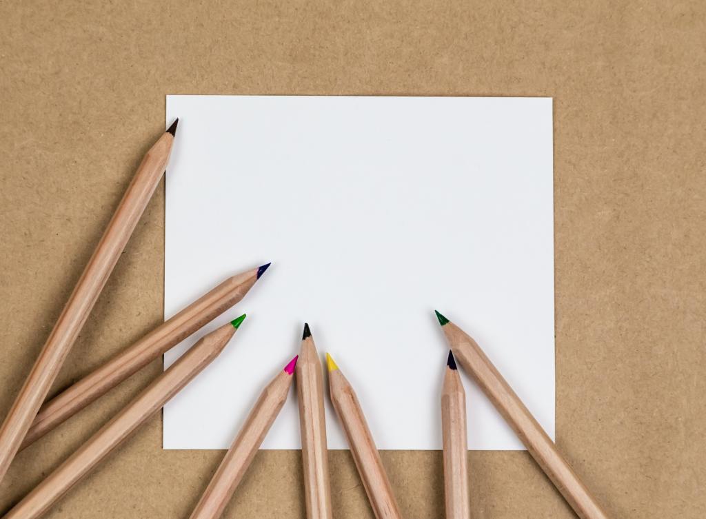 Image of blank piece of paper and pencil crayons. 