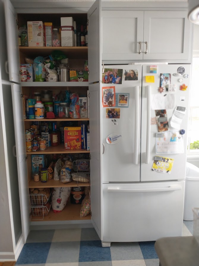 Image of refrigerator next to full-length pantry. 
